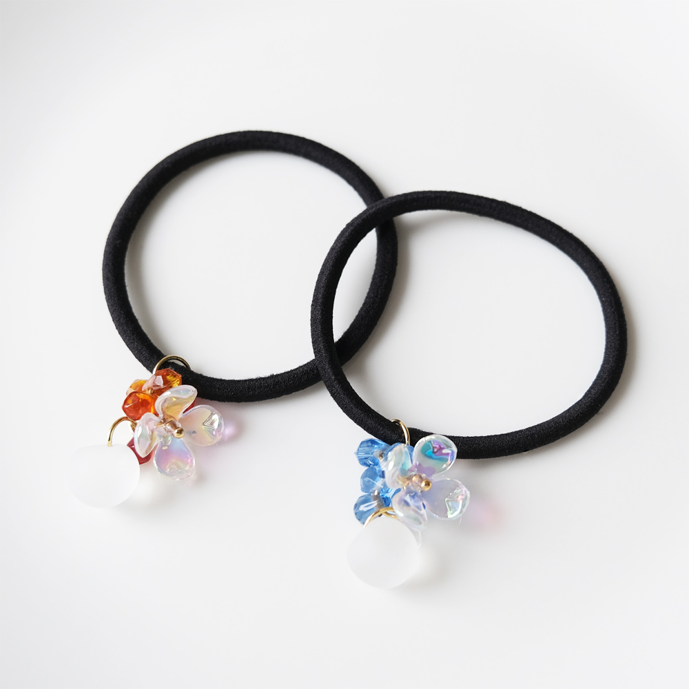 オーロラカラーのアクリルフラワーとカットが入ったビーズ、鈴丸をセットしたヘアゴムの画像
