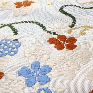 ＜お仕立て代込＞勝山さと子 「流水花束紋」 九寸名古屋帯 桜草木 / 白・灰水色と橙に金糸 の画像
